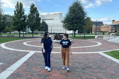 Two students from the shadowing program walking across campus talking