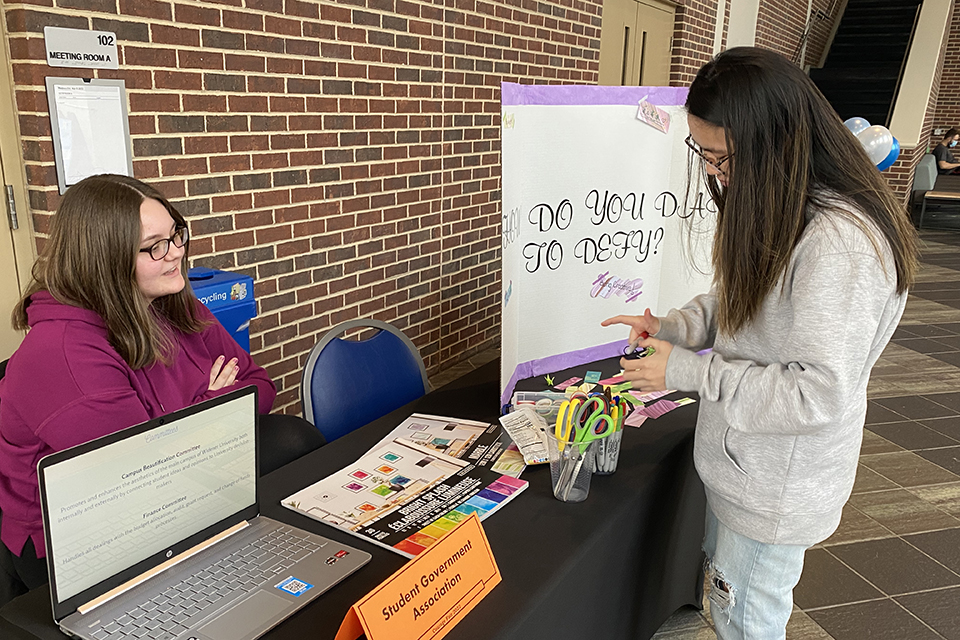 A student stands at the Student Government Association table at the Courage Fair in University Center