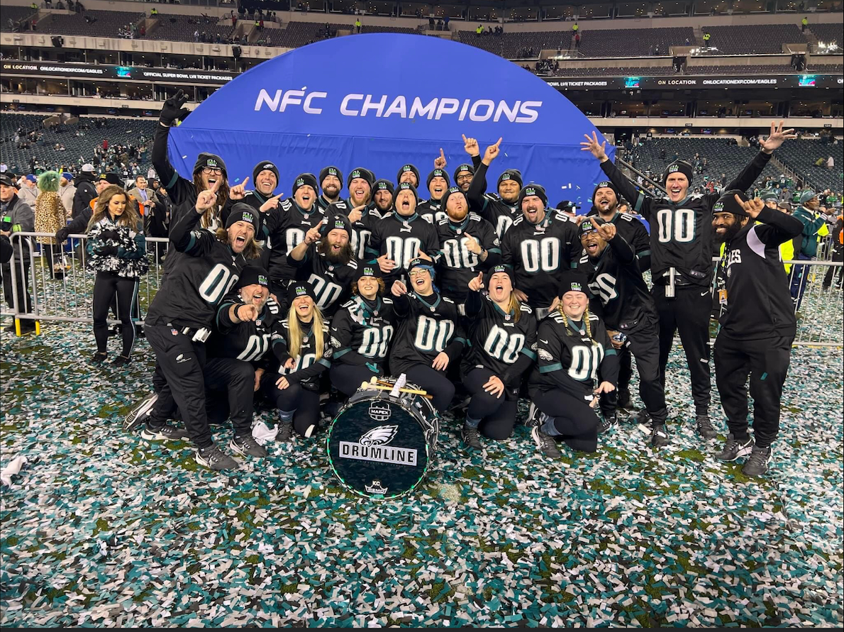 Kyree Cofer and the rest of the Eagles drumline pose for a photo on the field with an NFC Champions sign
