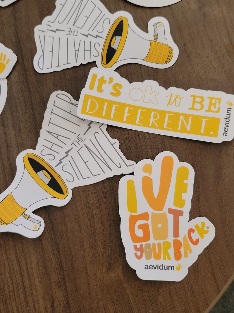 mental health stickers read "it's okay to be different" and "shatter the silence"
