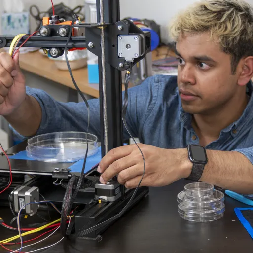 Student in lab working on device with petri dish