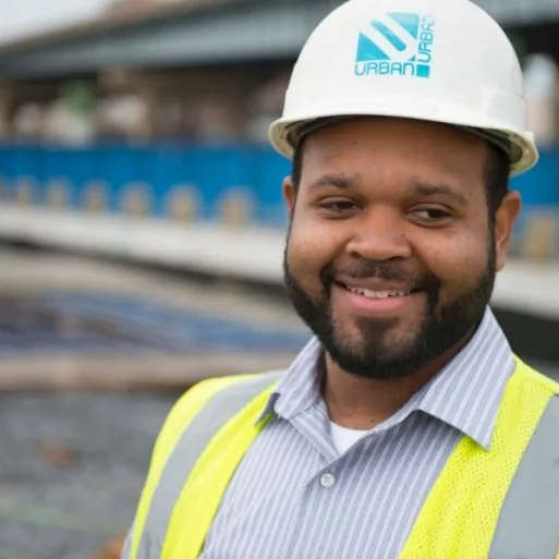 Kevin Brown poses in a hard hat and construction vest outdoors onsite.