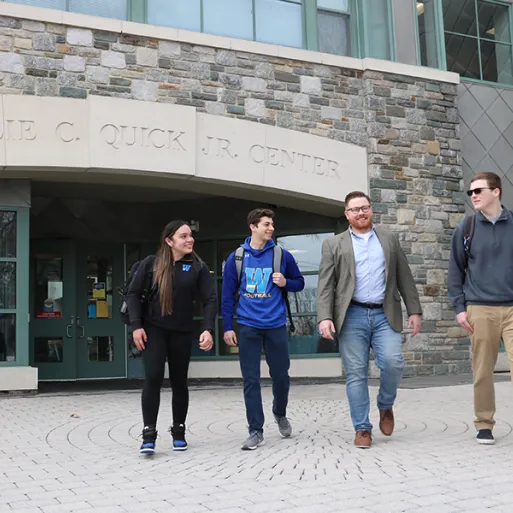 Ryan Raiker walks in front of Quick Center with three students