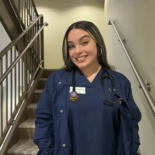 Nursing student Maritza Garcia poses in blue Widener scrubs