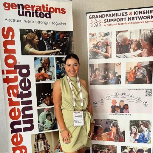Jess Mereshensky poses in a green dress in front of conference banners