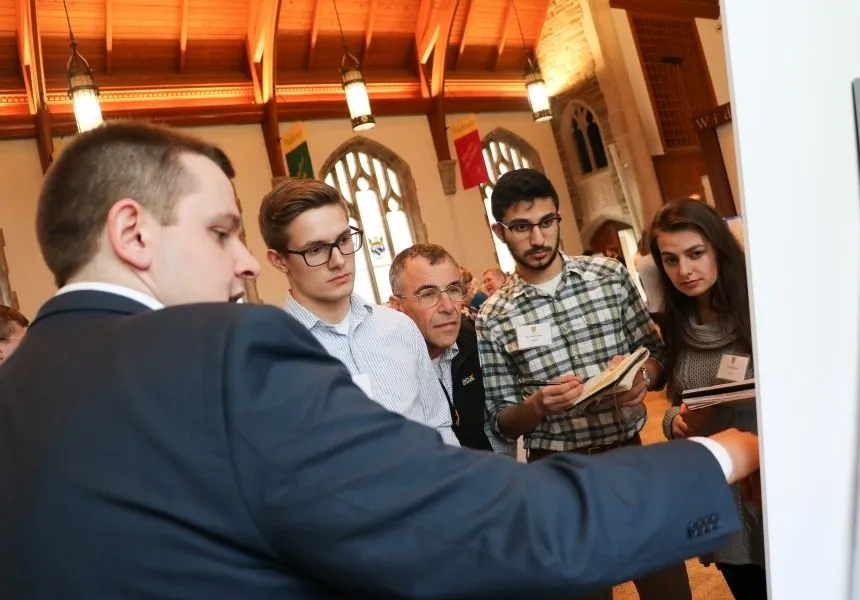 A male student presents his research to a group who listens closely.