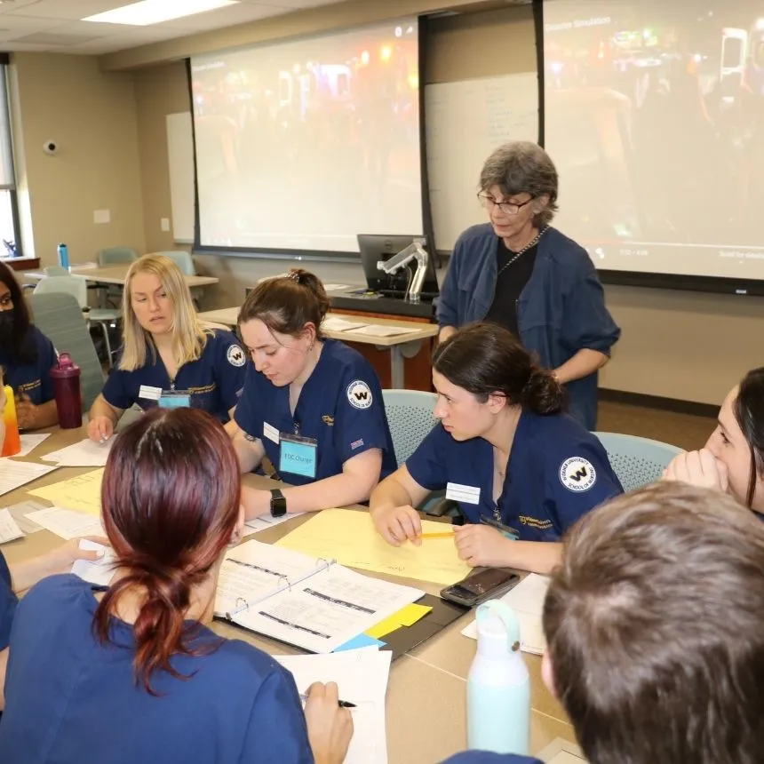 Students sit around a table in the simulated hospital command center.