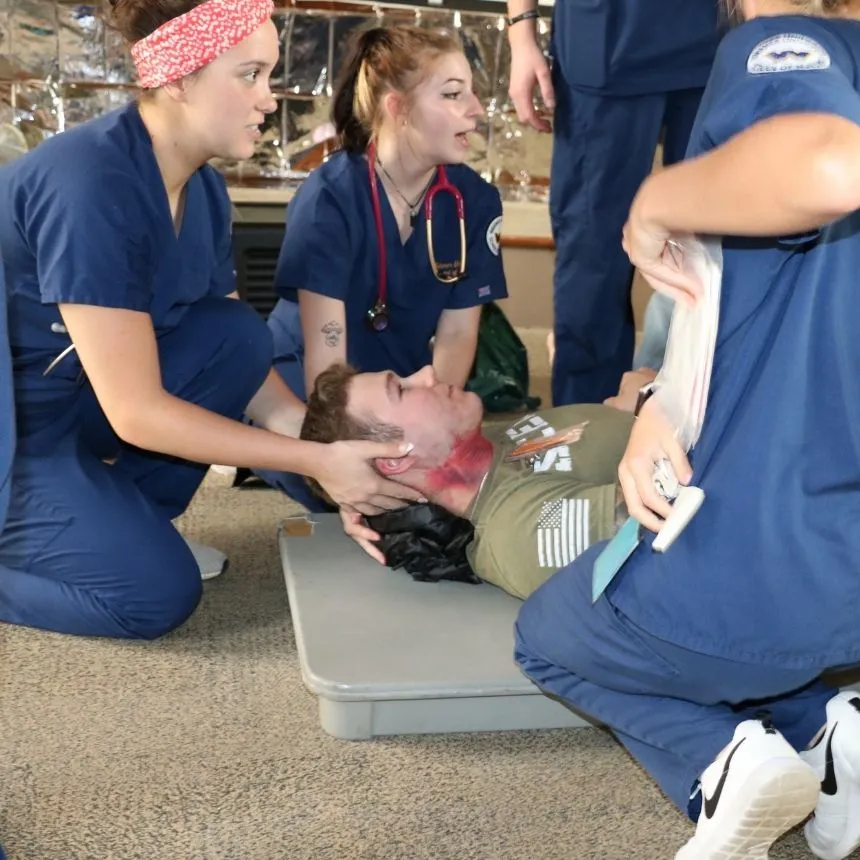 Female nursing students hold a victims head on a stretcher