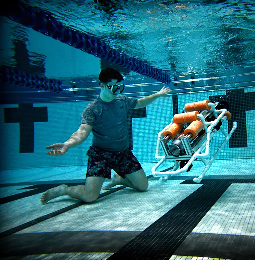 A male student is submerged underwater monitoring the submarine