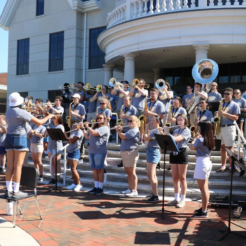 The marching band performing on the steps of Founders Hall