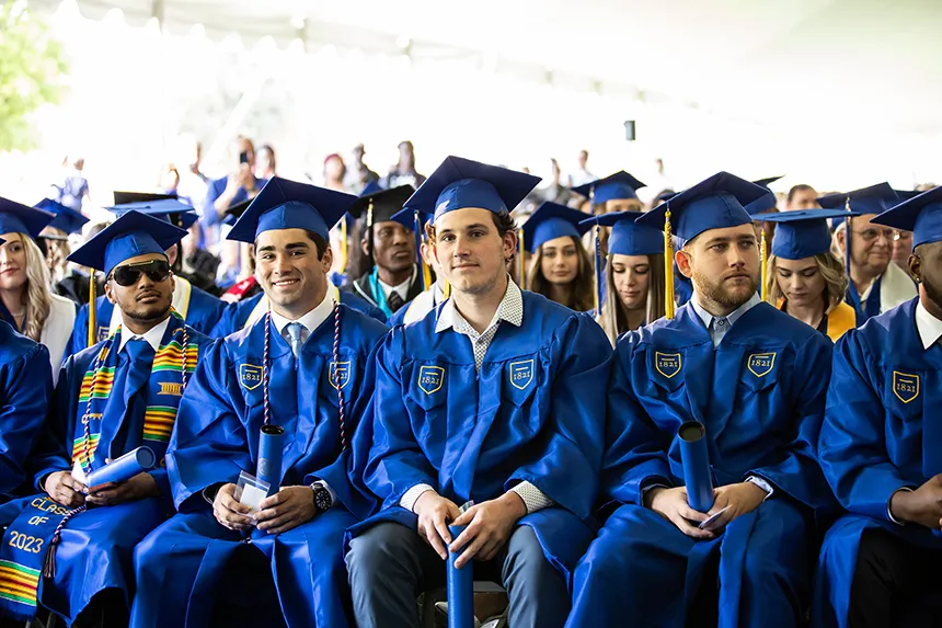 Grads in blue caps and gowns sitting at the commencement ceremony