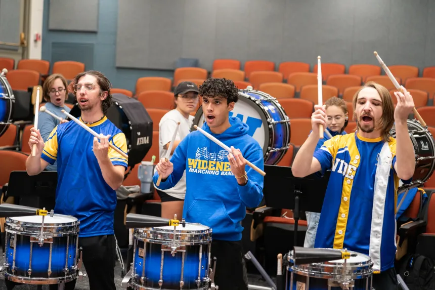 Three members of the marching band drumline as they play