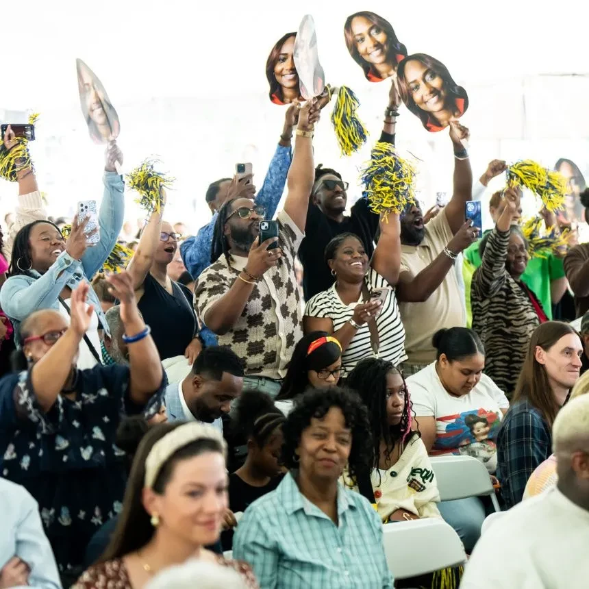 A family cheers for their graduate from the crowd with posters and signs.