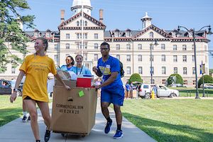 students move onto campus with boxes and old main building in background