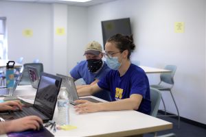 Two male civil engineer students engage and look a computer screen.