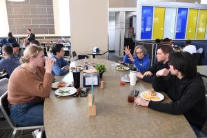 Five people, including President Wollman, sitting around a table in the Pride Cafe eating lunch.