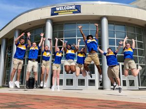 CREW Leaders in matching shirts jumping in mid-air in front of the University Center