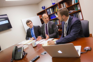 A student sits with colleagues in a conference room during an internship.