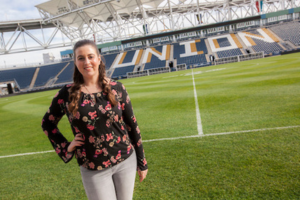 A Widener University student stands on the soccer field at her Philadelphia Union internship.