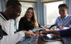 Three students seated around a table browse pamphlets for different majors and career options