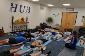 Widener student athletes meditate in H.U.B. on yoga mats during Check Up From the Neck Up mental health event