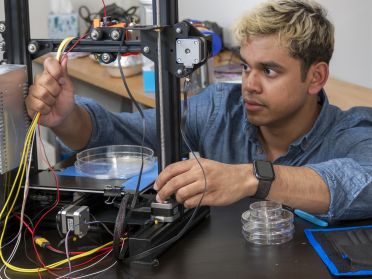 Student in lab working on device with petri dish