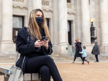 Samantha Peisino, holding her phone, sits outside of courthouse in Delaware County
