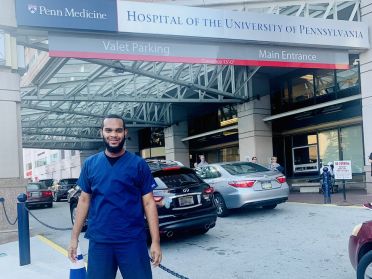 Jeremiah McFarland, standing outside a hospital, wearing blue scrubs