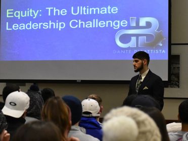 Dante DiBattista stands in front of a powerpoint screen speaking to a room of Widener students