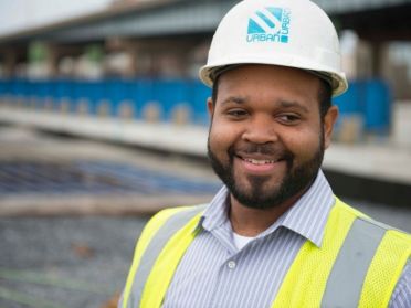 Kevin Brown poses in a hard hat and construction vest outdoors onsite.