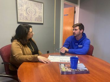 A female administrator sits with a male student discussing career planning.