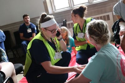 A female nursing student acts as an EMT tending to a patient during the disaster simulation event.