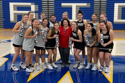Professor Donna McCloskey with members of the women's basketball team at Schwartz Athletic Center; each player is holding a pair of socks