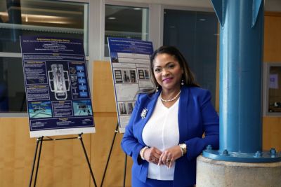 Engineering Dean Pamela McCauley in Kirkbride lobby with research posters behind her.
