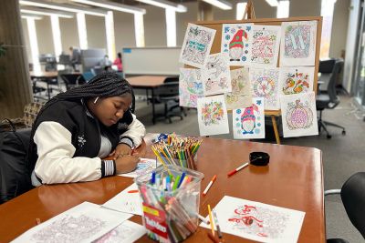 A student drawing and coloring at a table in the library