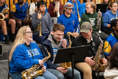 Alumni and current band members in a rehearsal with their instruments