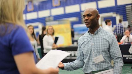 Adult student discussing resume with recruiter during a career fair