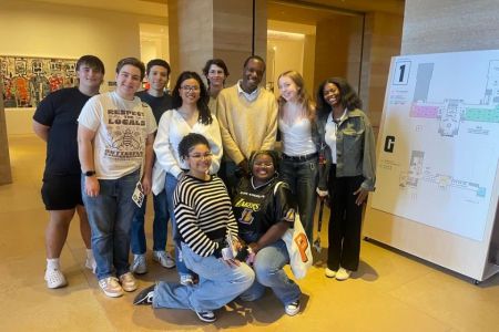 10 students huddled together in a museum smiling for the camera