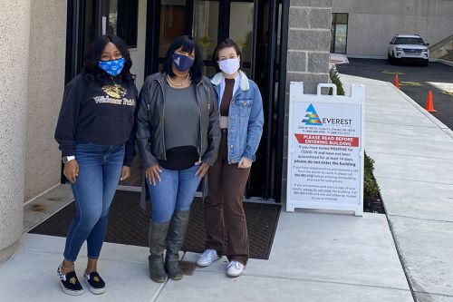 Two students and a community partner standing outside Everest Urgent Care