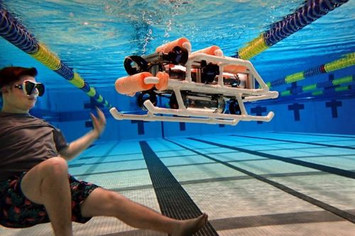 A robotics engineering student swims underwater while testing an autonomous submarine.
