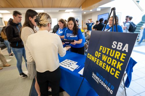 Students at the check in table with the event sign