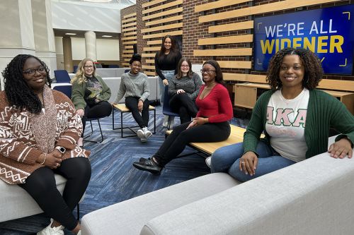 Seven female students sitting in chairs and on a sofa in the University Center Atrium