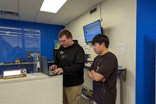 A male students get technology assistance from a student worker.