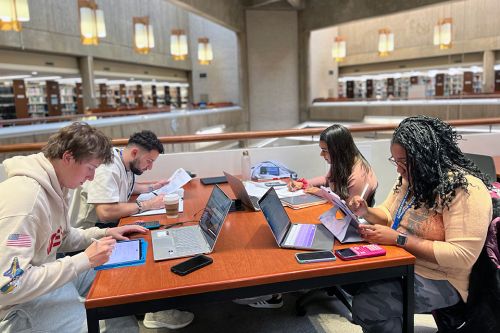 Four students studying at a table in the library