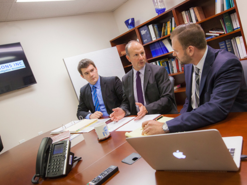 A Widener University students sits in a conference room with mentors at his internship.