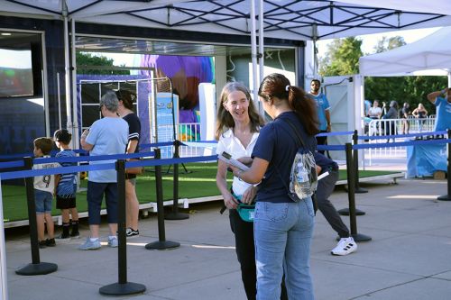 fan feedback header 960x640 A student talks with a fan about the survey, there is a tent and soccer themed activity in the background
