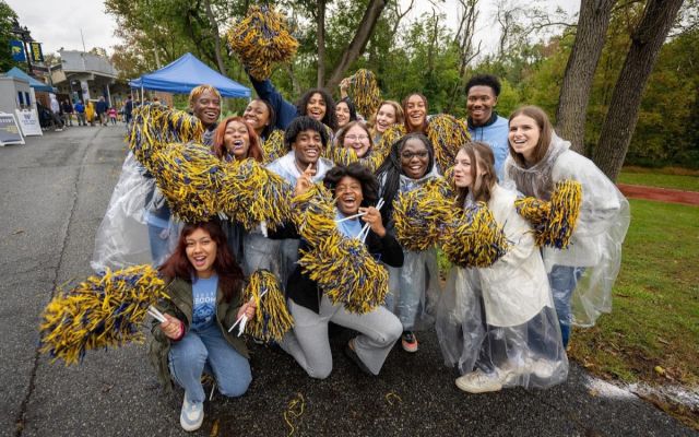 Group of students cheering with pompoms outside the homecoming tailgate