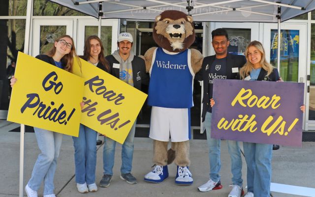 widener students hold Go Pride! Roar with Us signs with Widener mascot for admitted student day